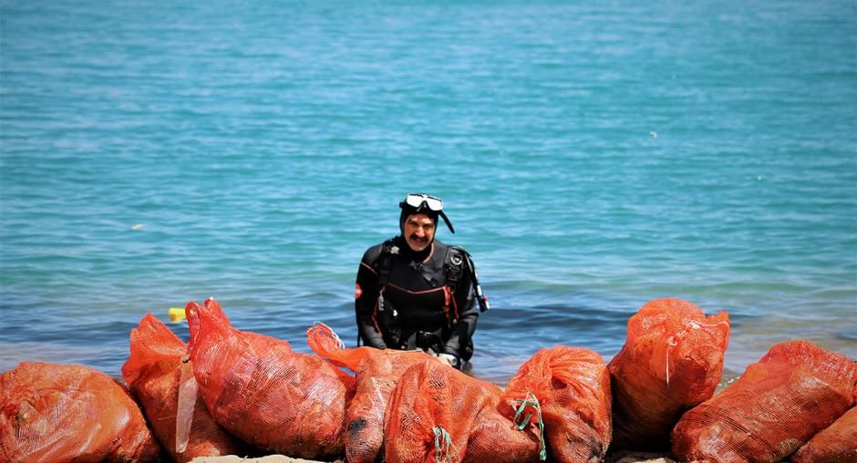 Taucher beseitigt Müll aus Meer.