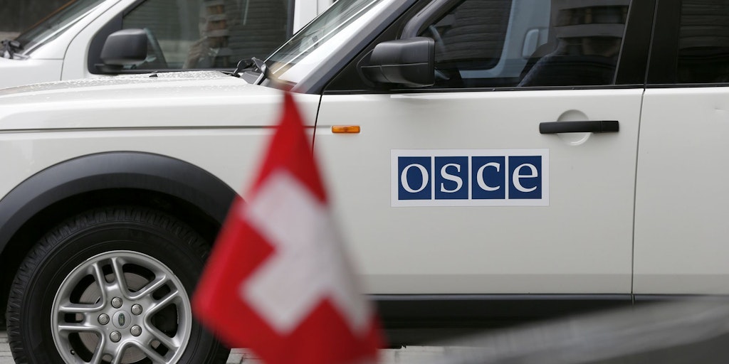 Cars of the OSCE convoy wait next to a limousine with the Swiss flag while Switzerland's Federal President Didier Burkhalter, OSCE Chairperson-in-Office, meets Ukraine's Prime Minister Arseniy Yatsenyuk during Burkhalter's visit in Kiev, Ukraine, Monday, April 14, 2014.